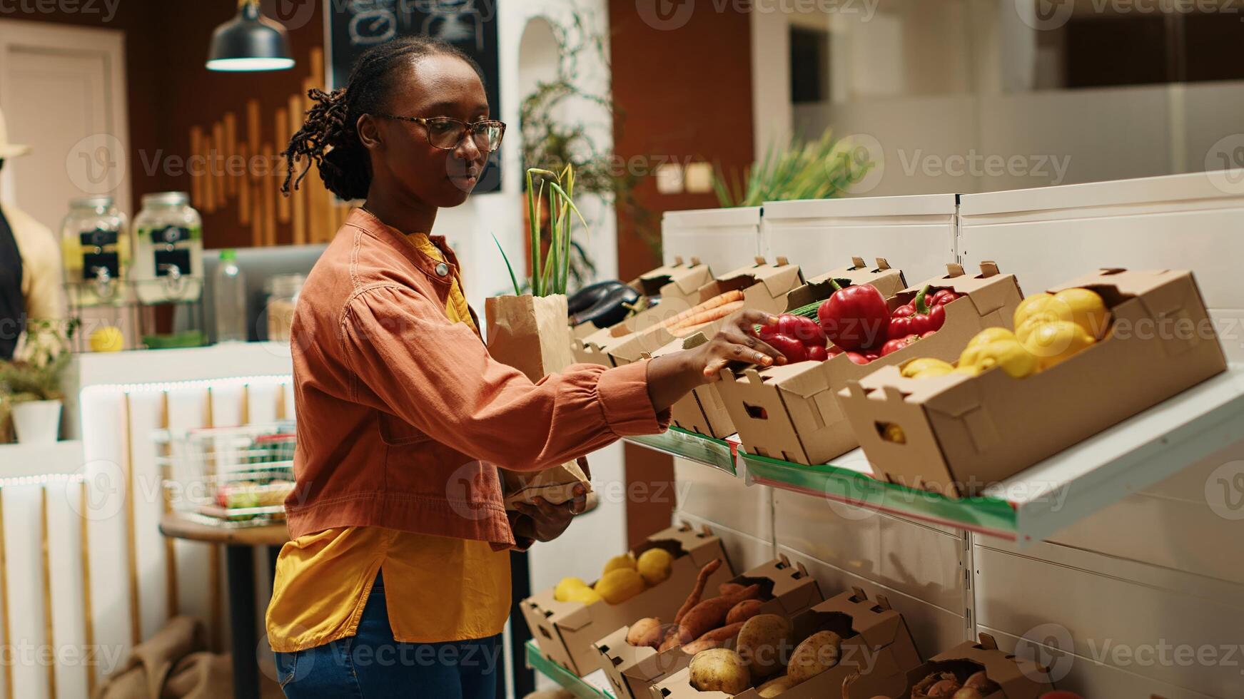 africano americano comprador escolhendo orgânico produzir a partir de caixotes, colocando frutas e legumes dentro uma papel saco para comprar. mulher compras para natural eco amigáveis produtos às local agricultores mercado. Câmera 1. foto