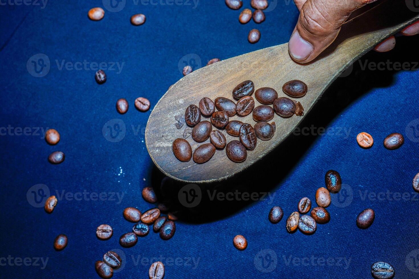 Preto café feijões estão visto fechar acima com uma de madeira colher em uma Preto pano. foto