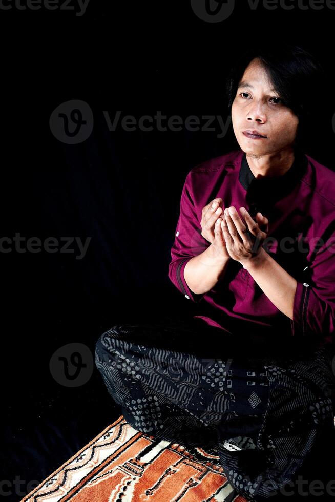 frente Visão do uma homem Rezar em uma oração esteira com uma Preto fundo. foto