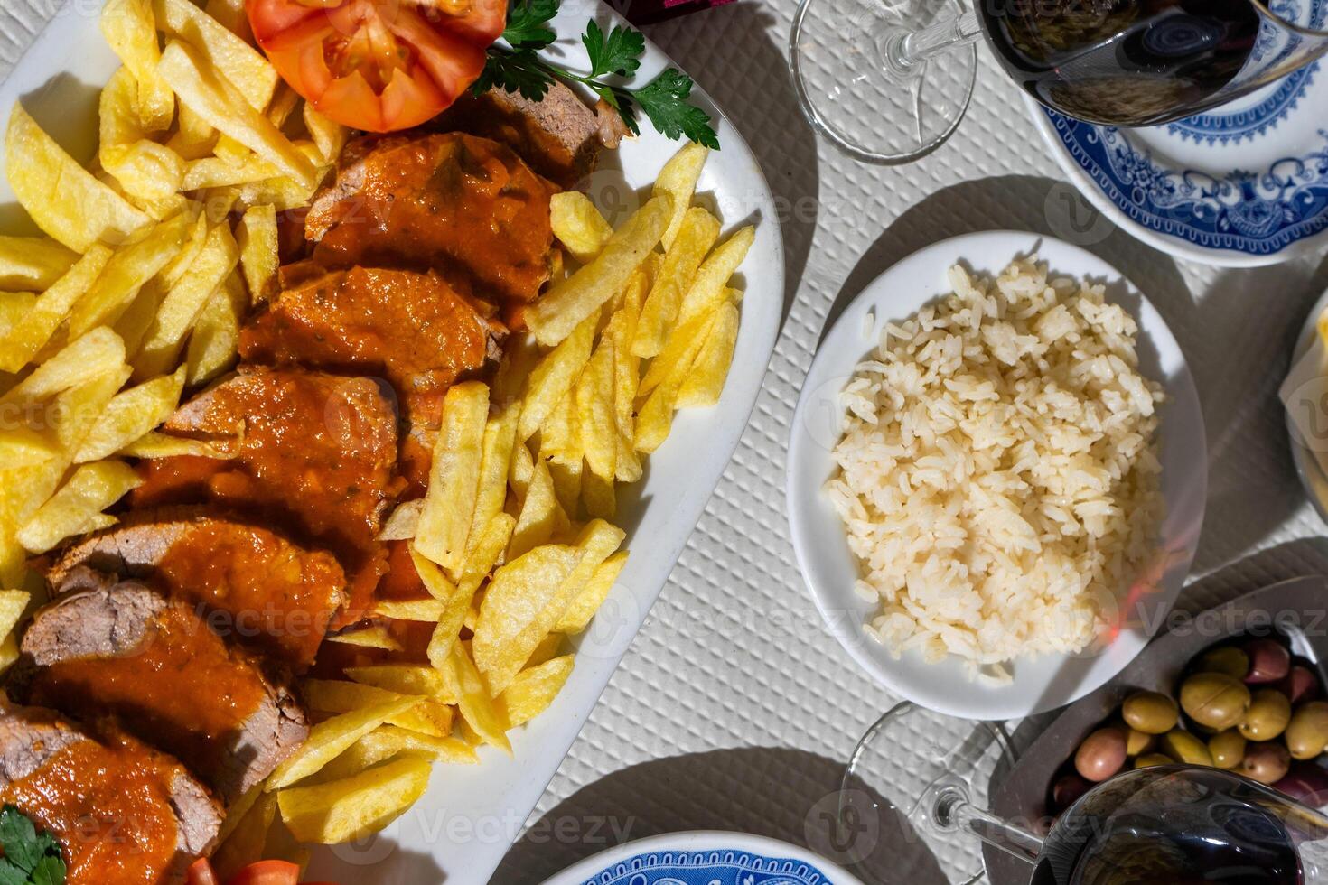 uma prato do vitela ensopado dentro uma rico tomate molho, servido com crocantes fritas, é apresentado em uma mesa às uma tradicional alentejo restaurante. a rústico configuração e forte prato crio uma convidativo atmosfera. foto