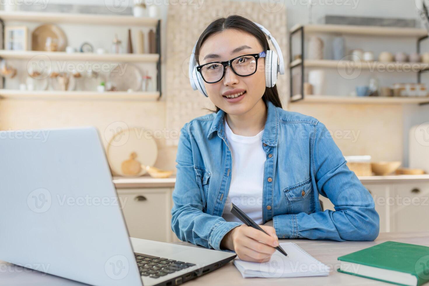 jovem ásia fêmea aluna estudando remotamente às lar, retrato do mulher com computador portátil em conectados Aprendendo usando computador portátil enquanto sentado dentro cozinha às casa foto