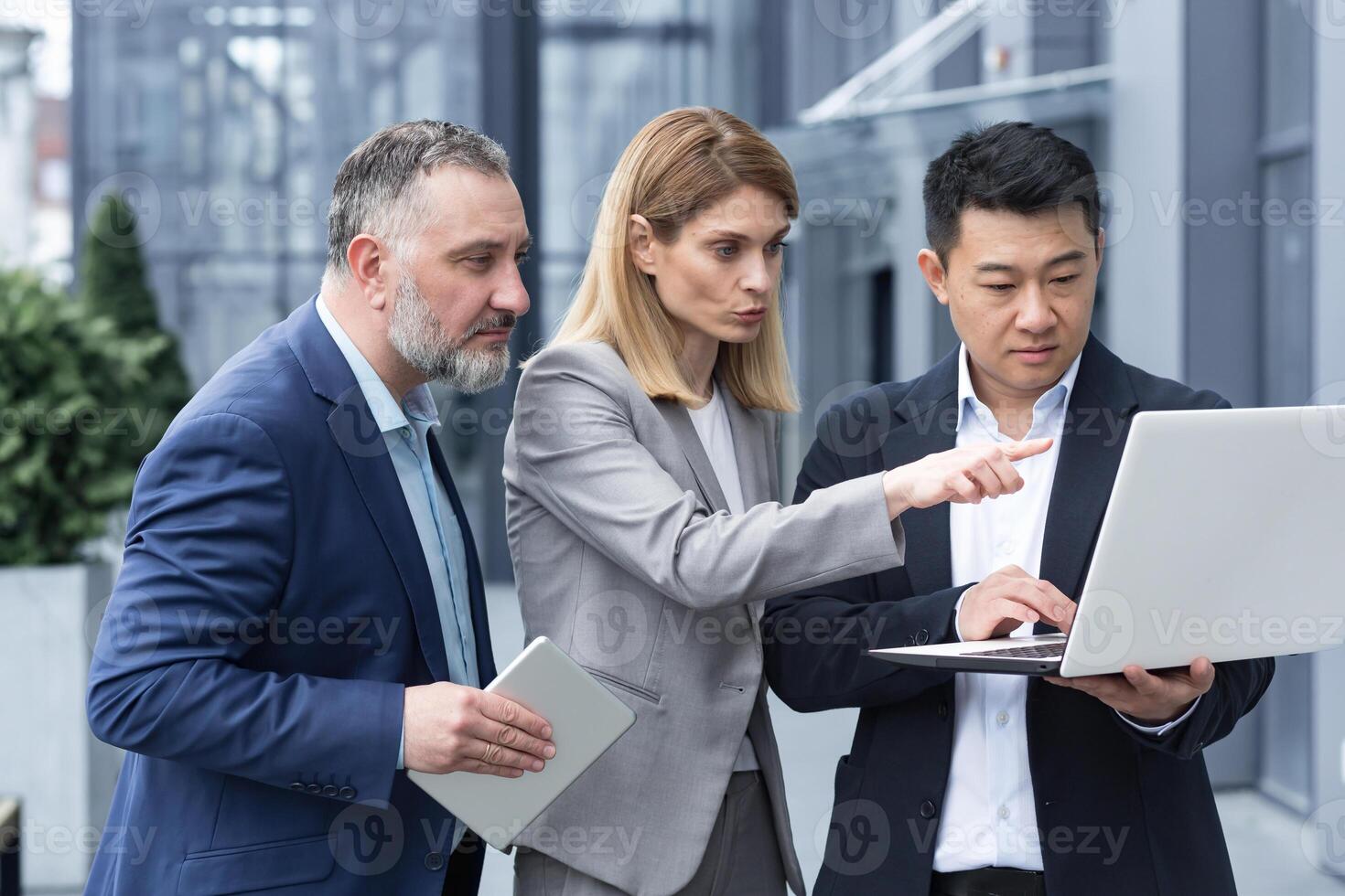 bem sucedido o negócio equipe, três colegas homem de negocios e empresária lado de fora escritório construção discutindo atual planos e gerenciamento, olhando às computador portátil tela, discutindo e consultando foto