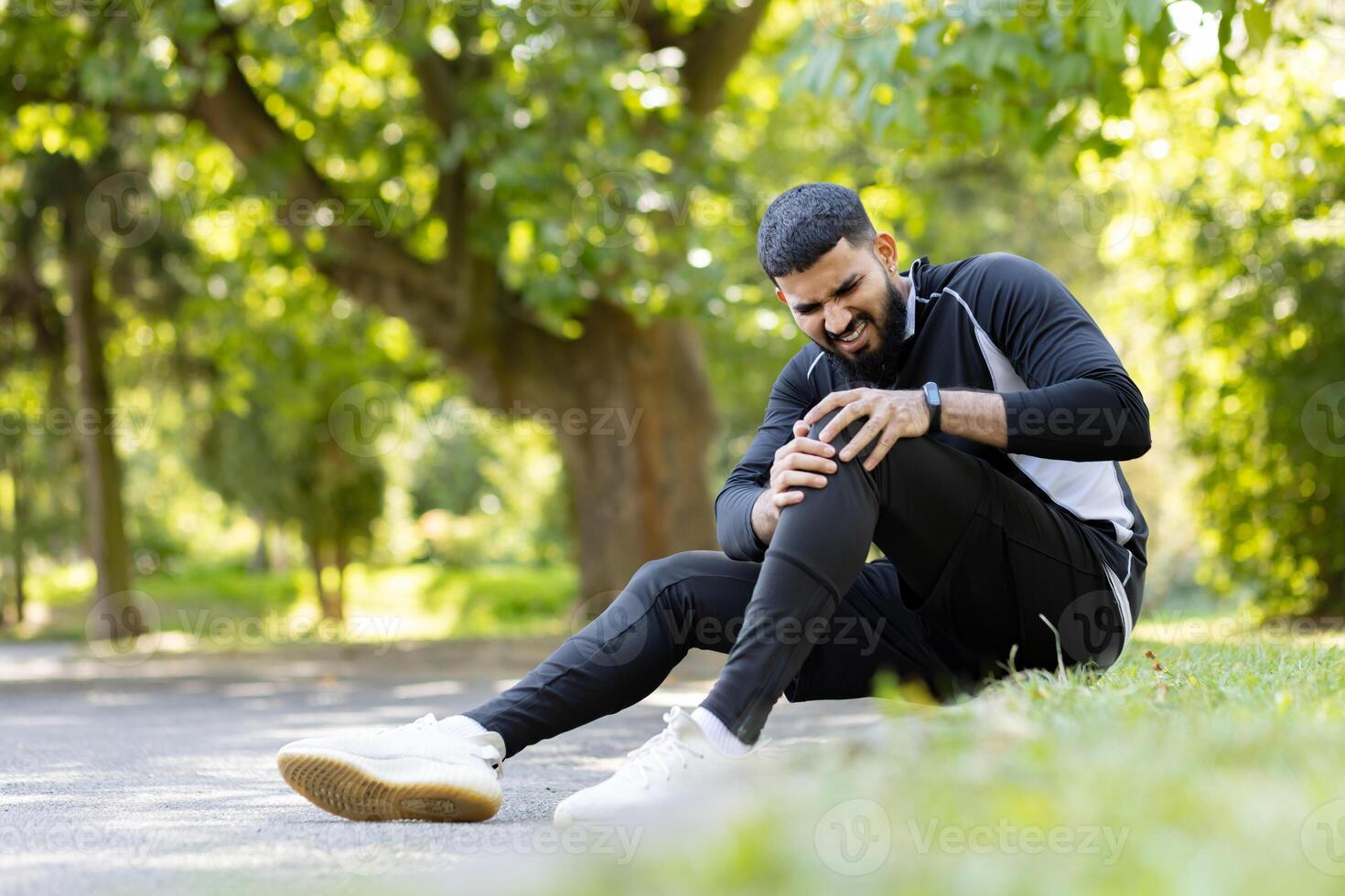 uma masculino atleta detém dele joelho dentro dor, sentindo-me desconforto durante uma ginástica sessão dentro uma ensolarado parque contexto. foto