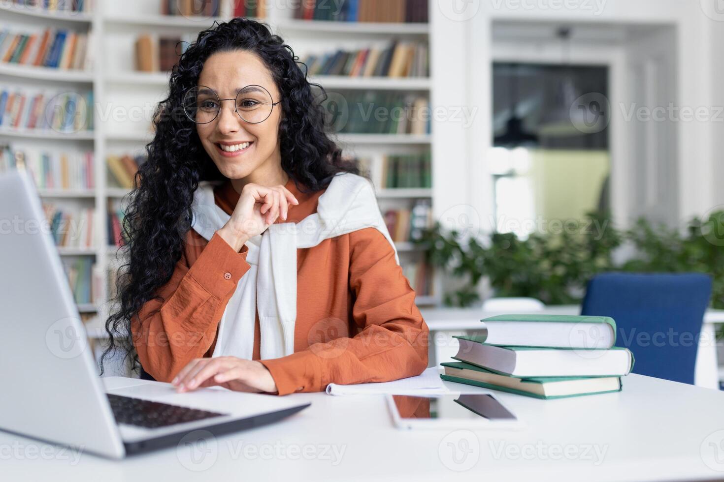 fêmea aluna com computador portátil lendo conectados curso, latim americano mulher sorridente e satisfeito com independente conectados Aprendendo sentado dentro universidade campus dentro biblioteca. foto