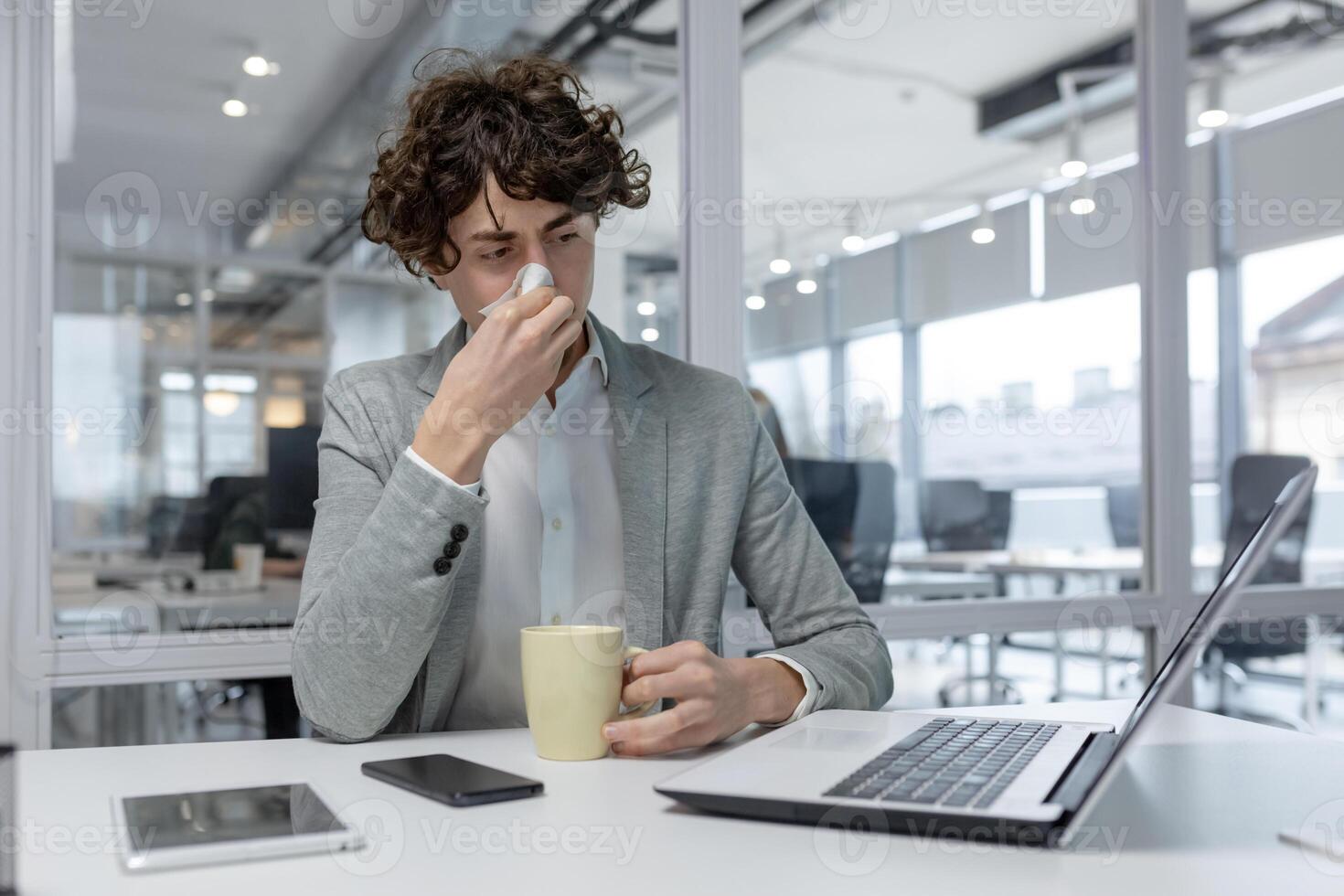profissional masculino com encaracolado cabelo bebericando café enquanto concentrando em computador portátil trabalhos dentro uma brilhante contemporâneo escritório espaço. foto