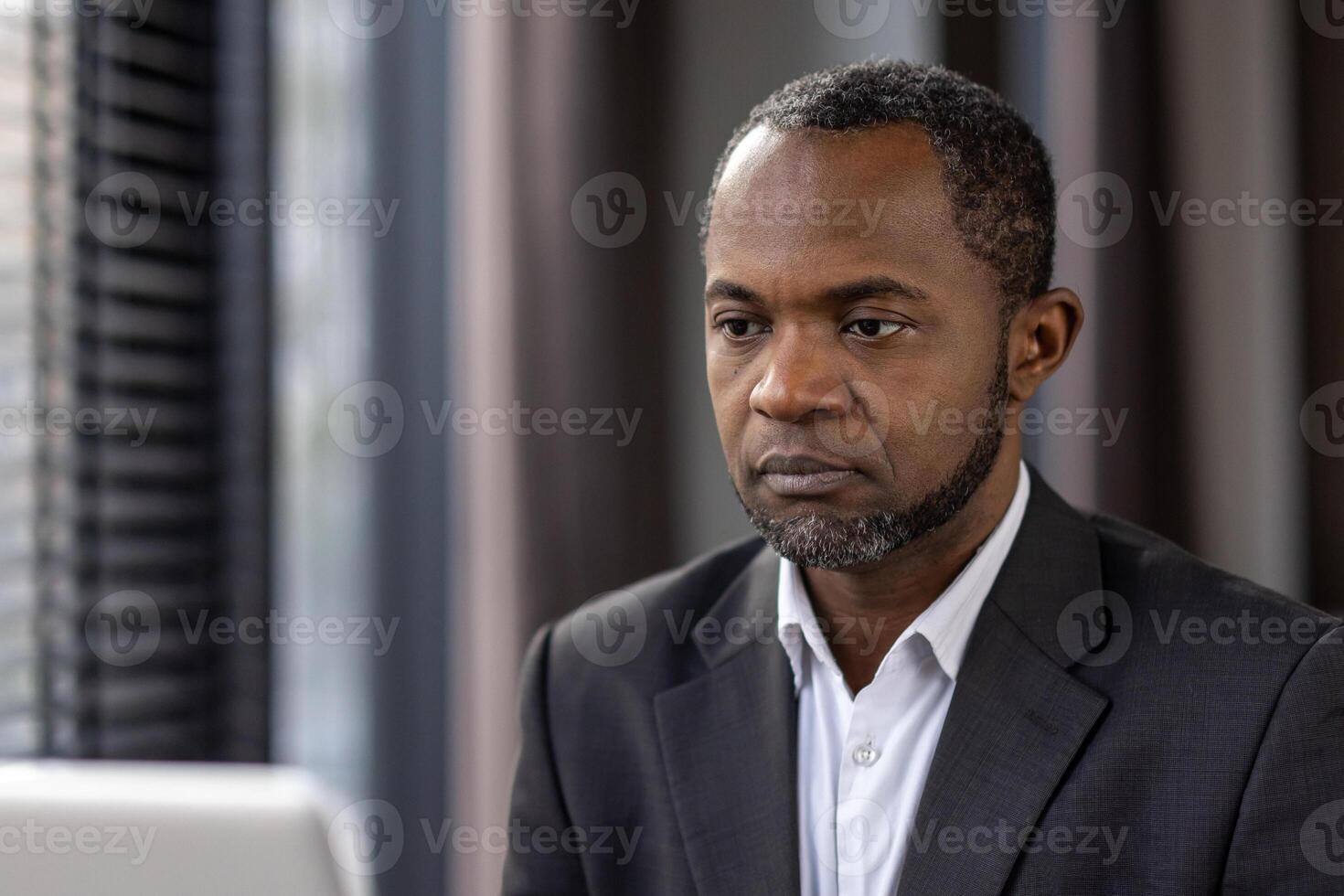 pensativo africano americano homem de negocios concentrando atentamente dentro uma moderno escritório contexto, incorporando profissionalismo e dedicação. foto
