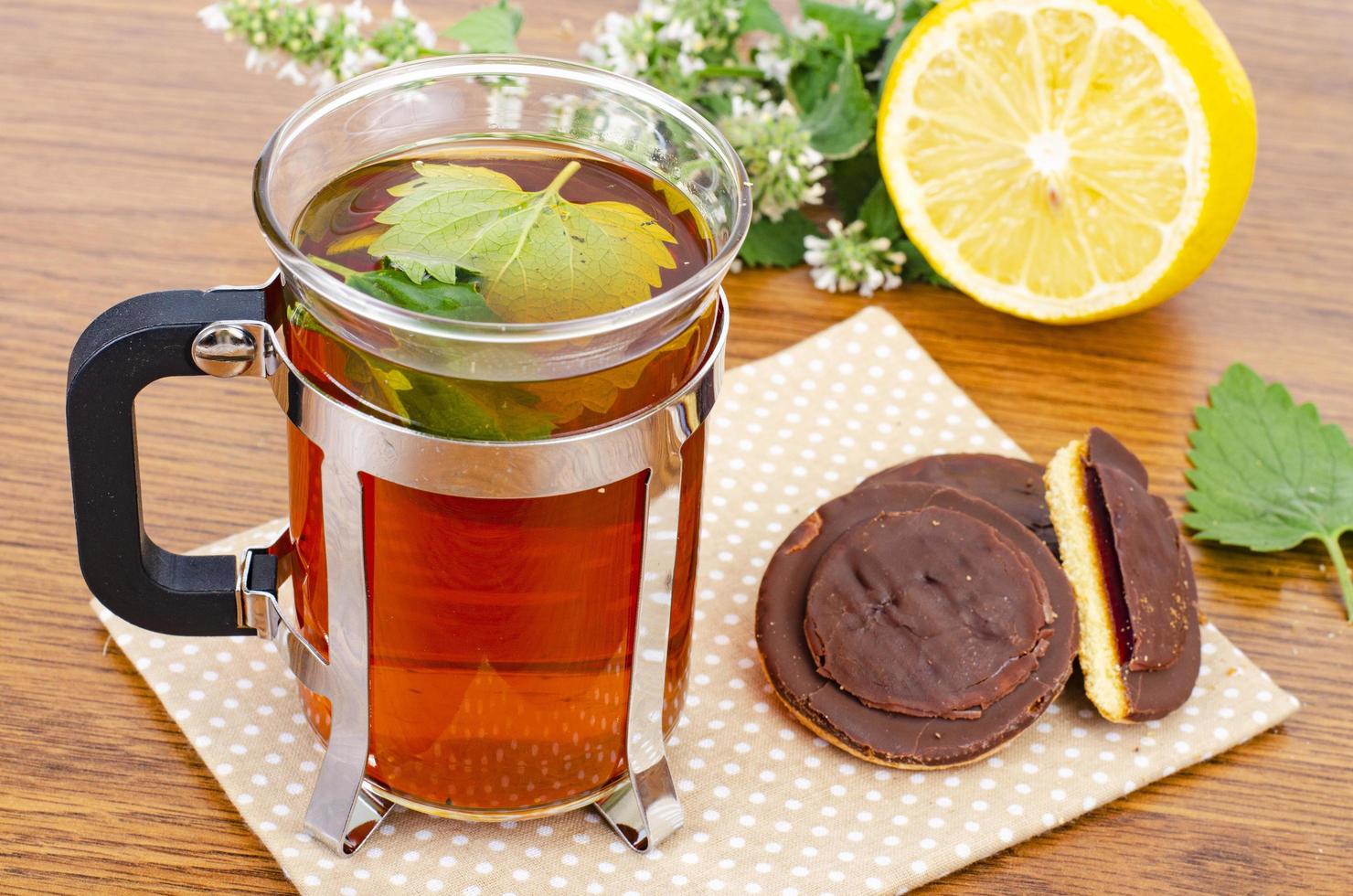 copo de chá, erva-cidreira fresca e biscoitos na mesa. foto