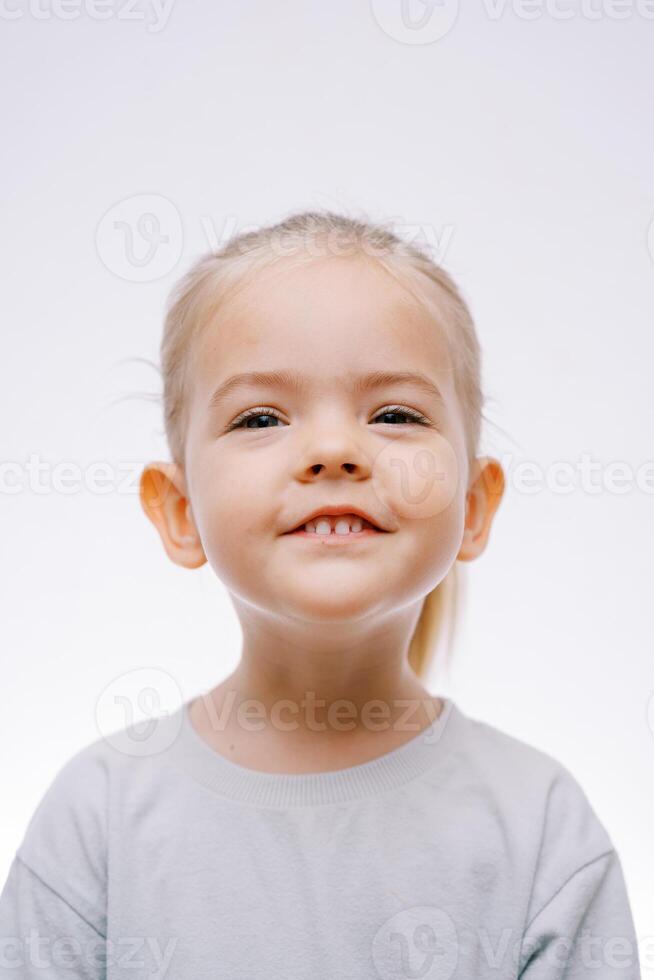 retrato do uma pequeno sorridente menina em uma cinzento fundo foto