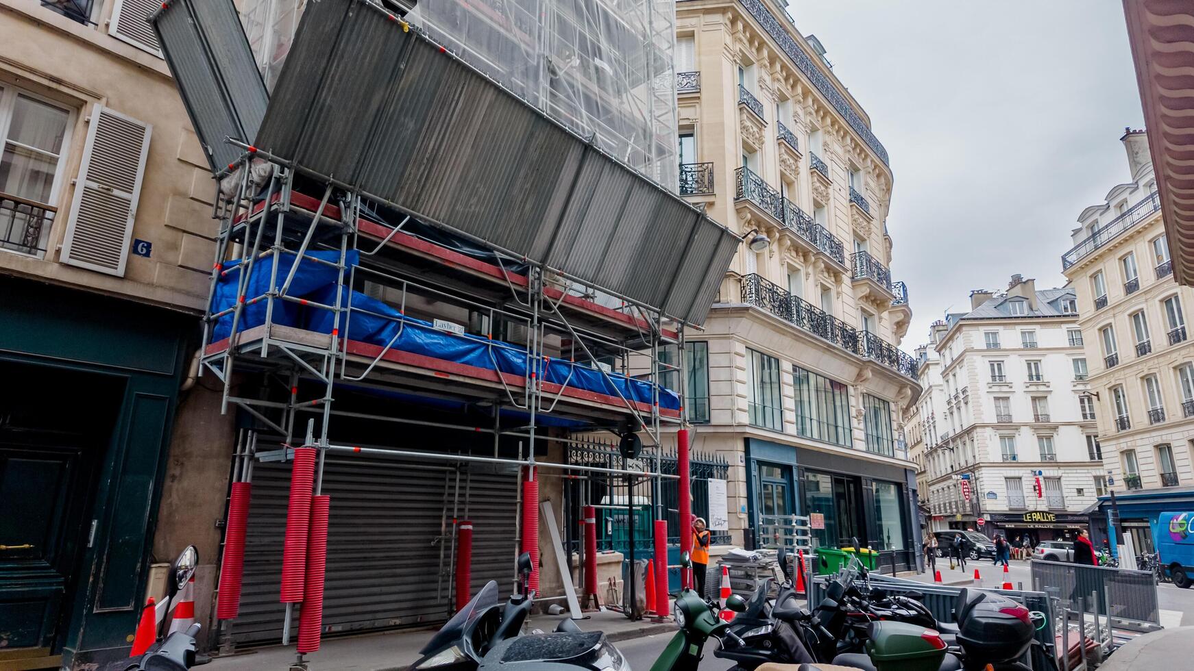 urbano renovação dentro Paris com andaimes em uma construção no meio estacionado motocicletas, capturado em abril 14, 2024, ideal para temas do construção e cidade manutenção foto