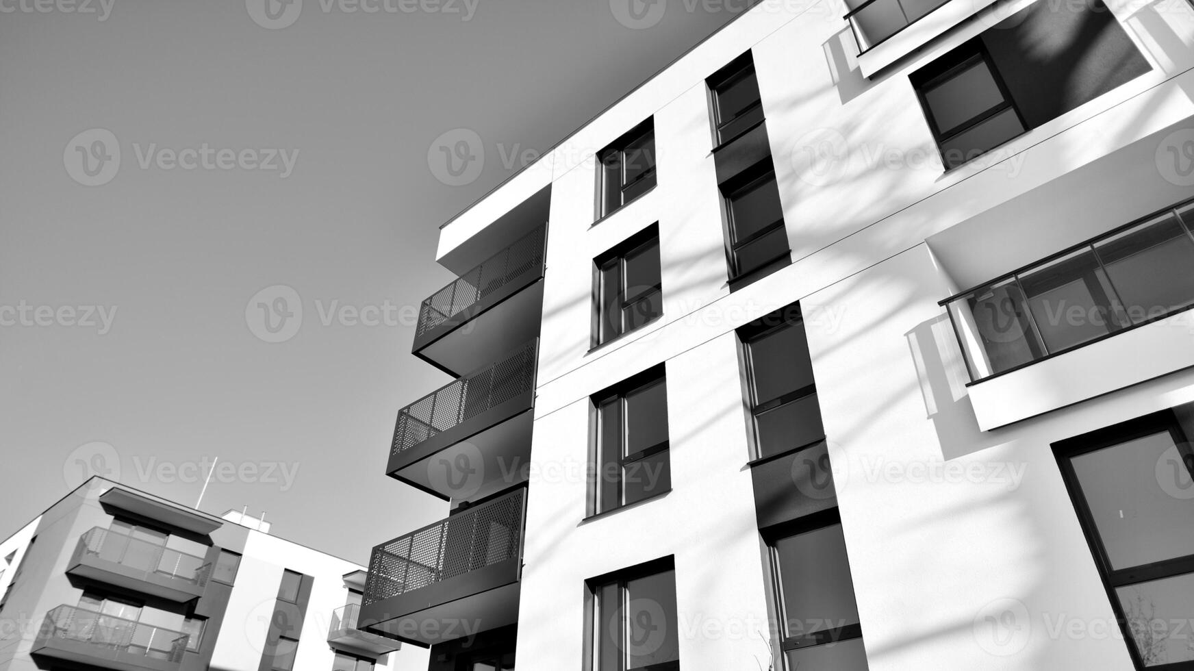 fragmento do uma fachada do uma construção com janelas e varandas. moderno apartamento edifícios em uma ensolarado dia. fachada do uma moderno apartamento prédio. Preto e branco. foto