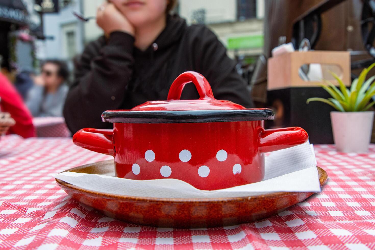 bratislava, Eslováquia. marcha 27, 2024. tradicional eslovaco restaurante grande mães localizado dentro a cidade Centro. pessoas estão jantar fora. tradicional repolho sopa é servido dentro a vermelho fundida ferro Panela. foto