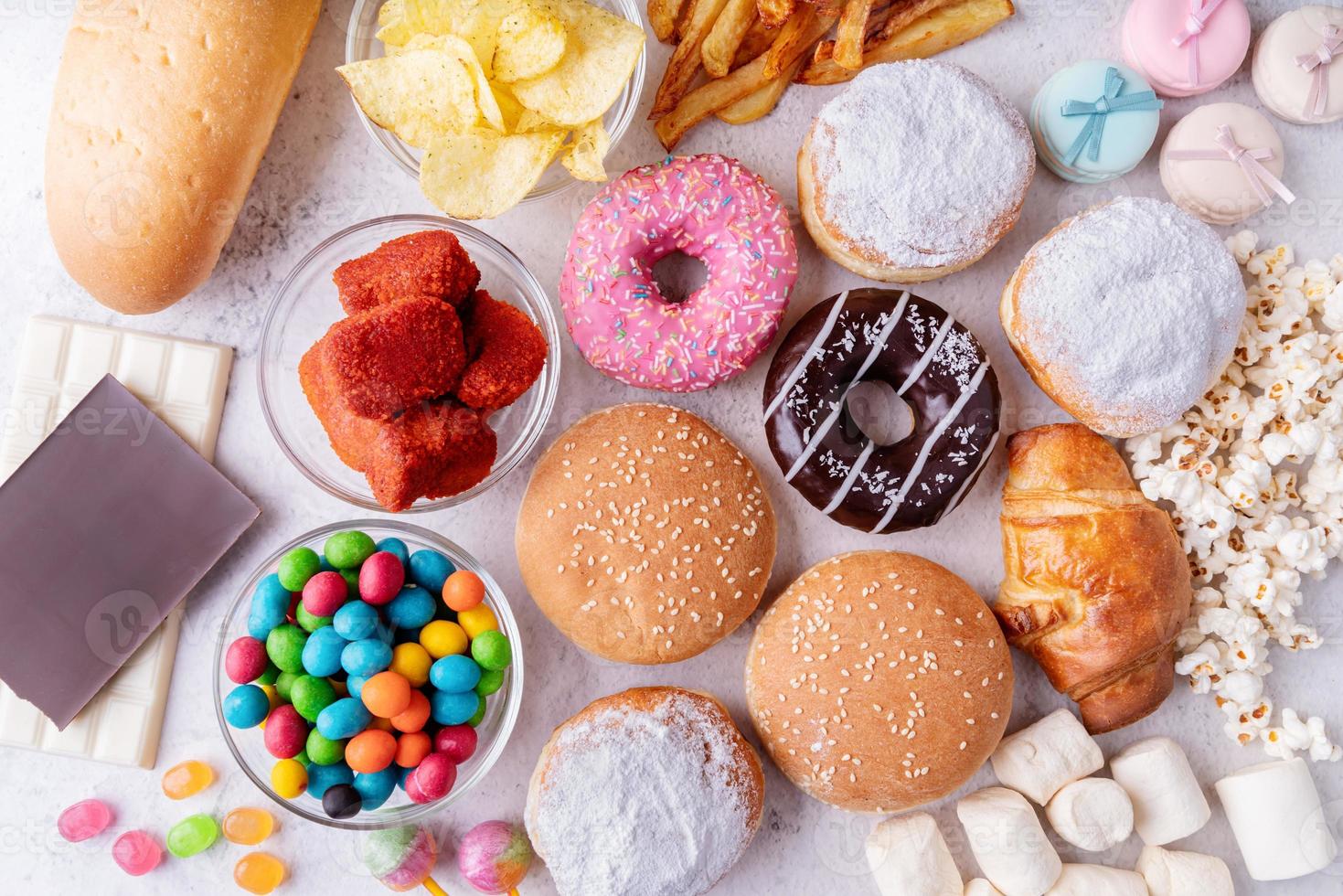 alimentos não saudáveis e fast food com donuts, chocolate, hambúrgueres e doces vista superior foto