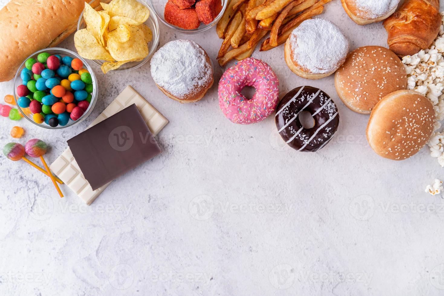 alimentos não saudáveis e fast food com donuts, chocolate, hambúrgueres e doces vista superior com espaço de cópia foto