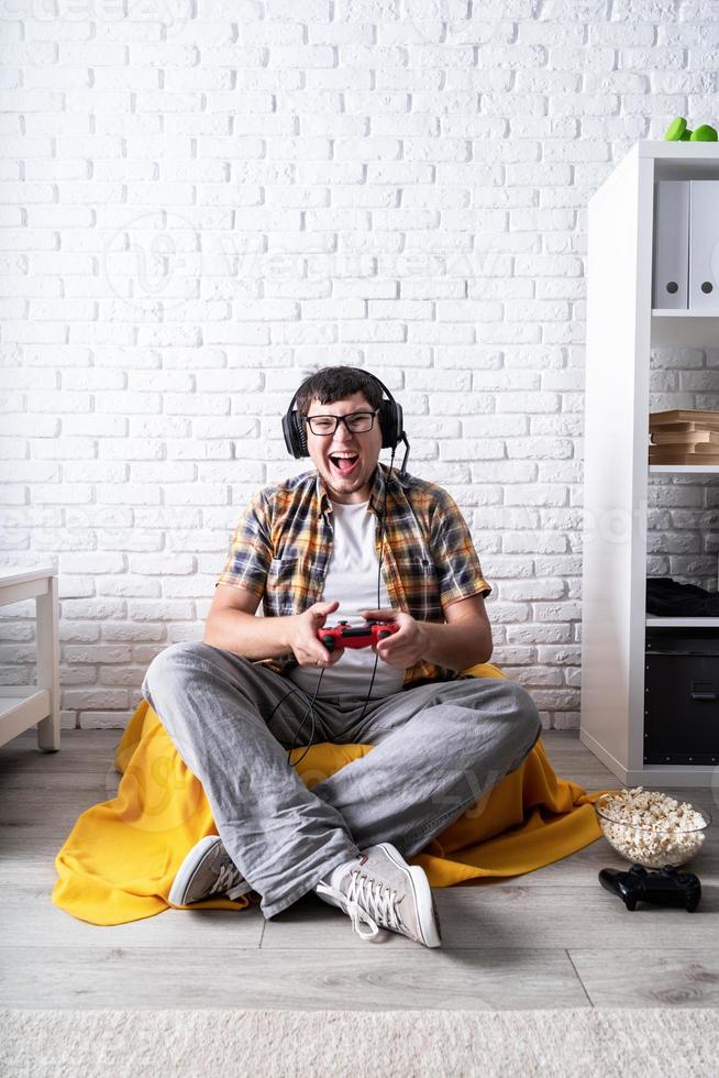 jovem animado jogando videogame em casa apreciando sua vitória foto