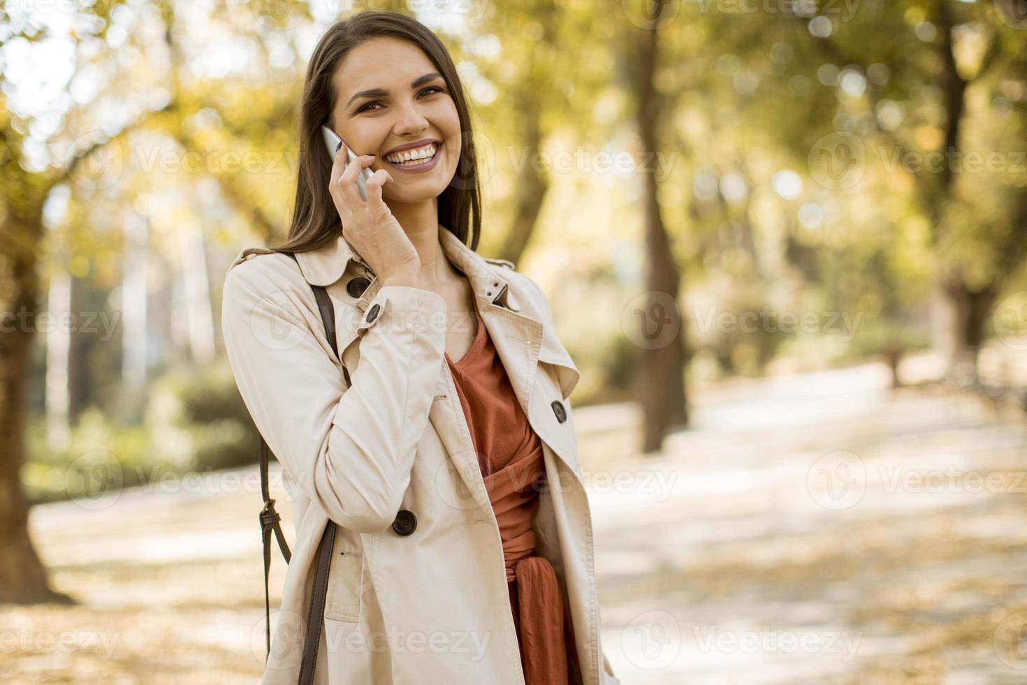 jovem feliz usando telefone celular no parque outono foto