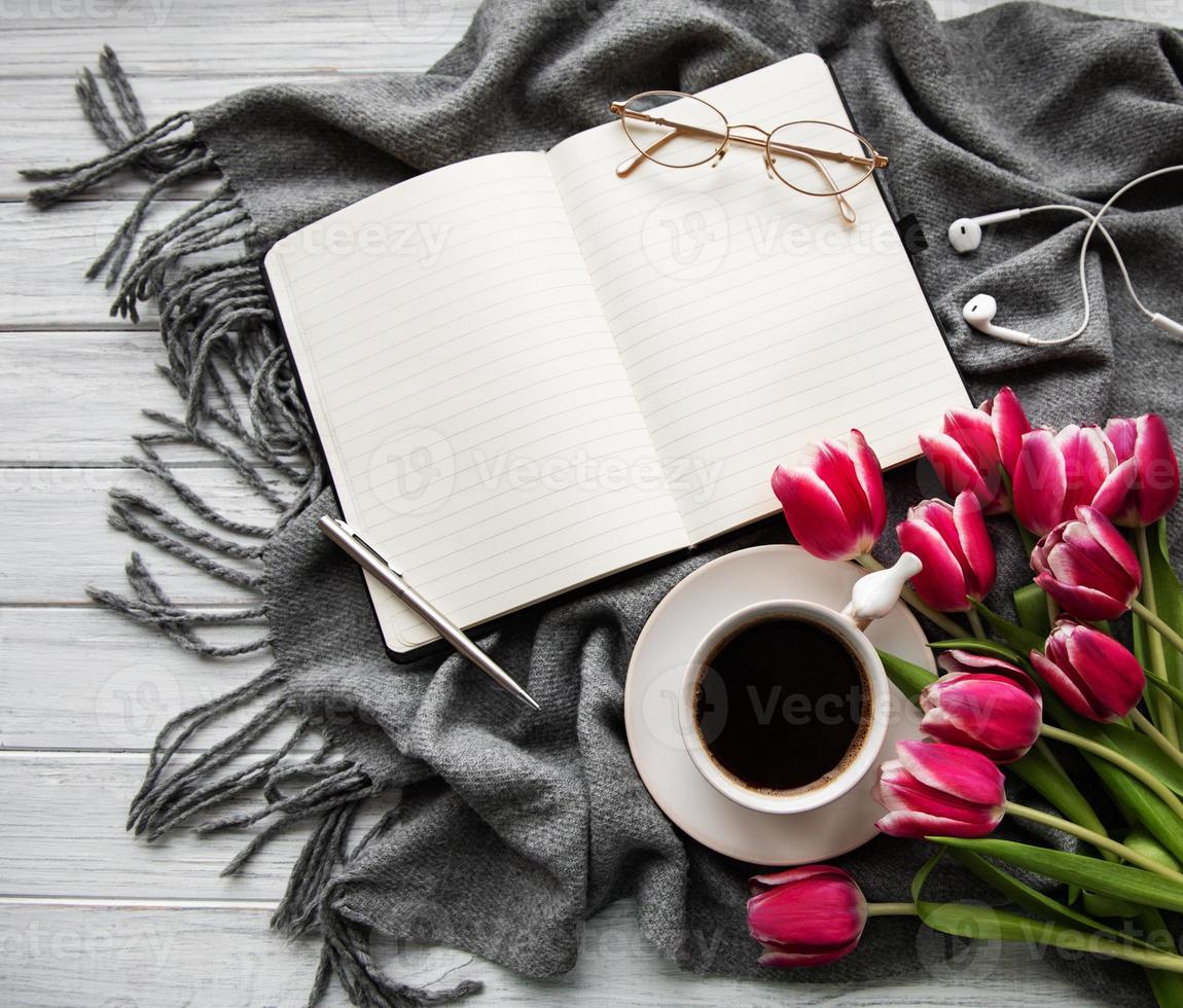 caderno, xícara de café e tulipas cor de rosa foto