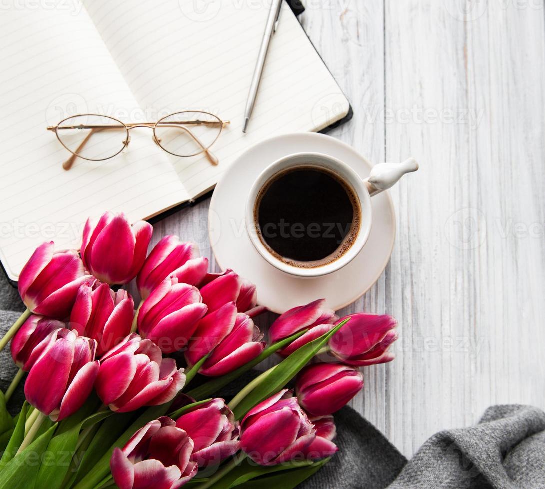 caderno, xícara de café e tulipas cor de rosa foto