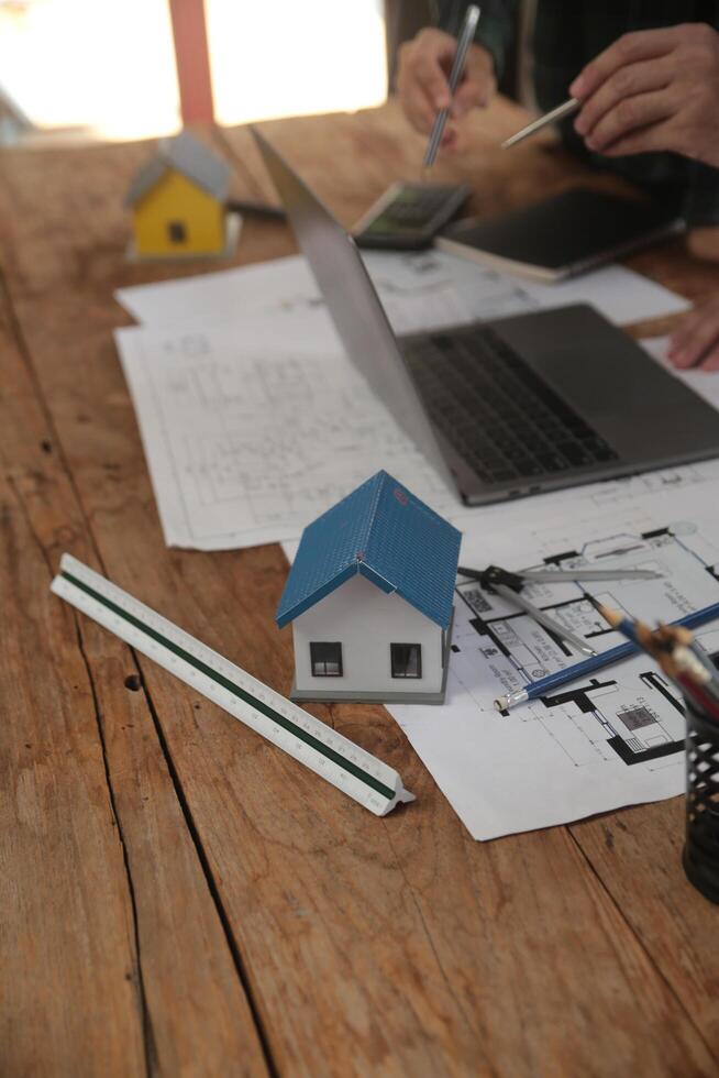 engenheiros estão consultando a equipe para Projeto a arquitetônico estrutura para clientes com plantas e construção modelos para trabalhos às escritório. foto