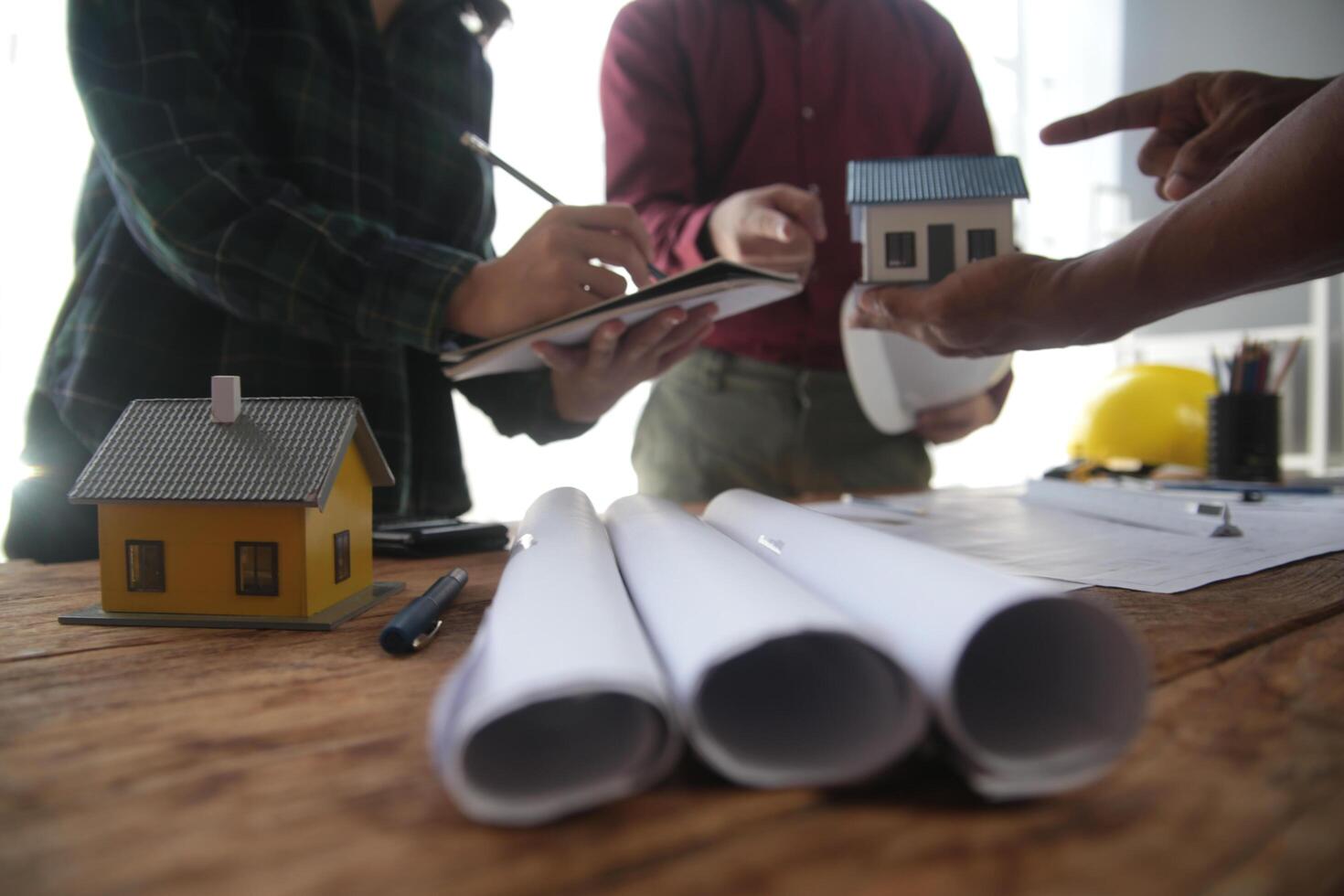 engenheiros estão consultando a equipe para Projeto a arquitetônico estrutura para clientes com plantas e construção modelos para trabalhos às escritório. foto