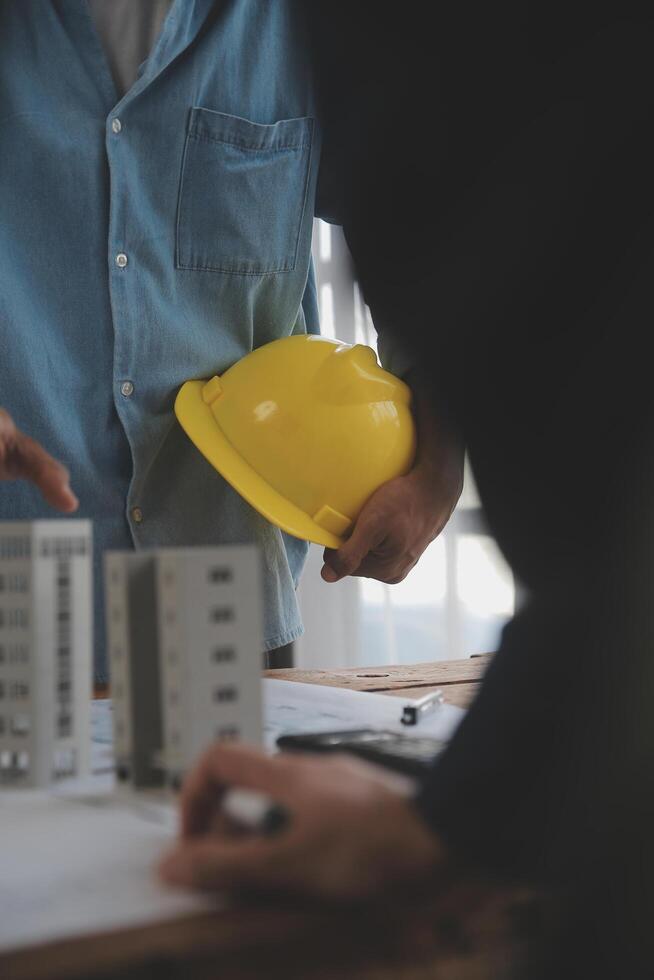 conceito de construção e estrutura de reunião de engenheiro ou arquiteto para projeto trabalhando com parceiros e ferramentas de engenharia na construção de modelo e projeto no local de trabalho, contrato para ambas as empresas. foto