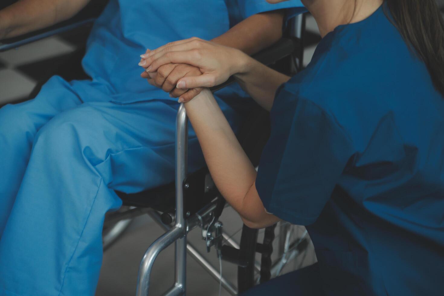 médico dando ter esperança. fechar acima tiro do jovem fêmea médico inclinado frente para sorridente idosos senhora paciente segurando dela mão dentro Palmeiras. mulher zelador dentro branco casaco apoiando encorajando velho pessoa foto