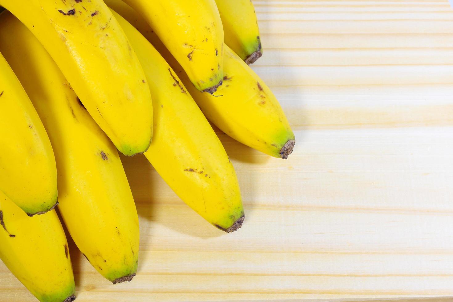 cacho de banana isolado em mesa de madeira, vista de cima foto