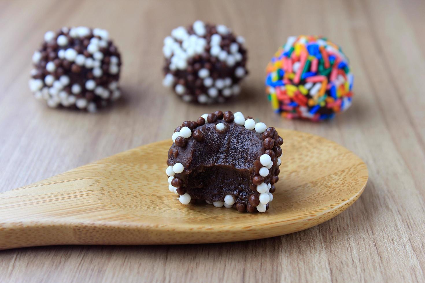 brigadeiro, brigadeiro, chocolate doce típico da culinária brasileira coberto por partículas, em fundo de madeira. foto