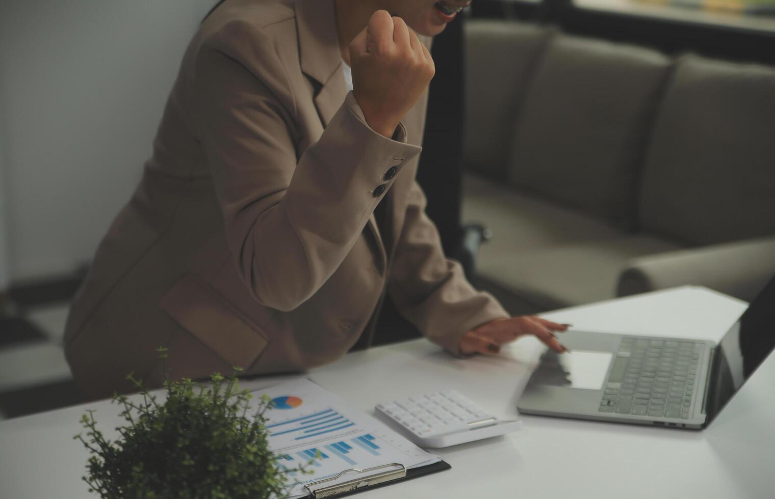 jovem feliz empresária usando computador dentro moderno escritório com colegas. à moda lindo Gerente sorridente, trabalhando em financeiro e marketing projetos. bebendo chá ou café a partir de uma caneca. foto