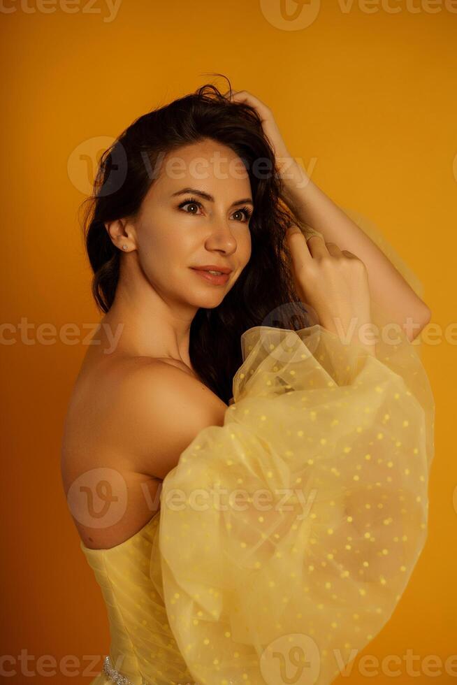 perfil retrato do uma lindo meia idade mulher dentro uma amarelo vestir, dela cabelo puxado acima contra uma amarelo fundo foto