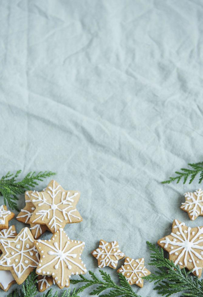 ramos de abeto com biscoitos de gengibre de Natal no fundo de tecido amassado de linho verde foto