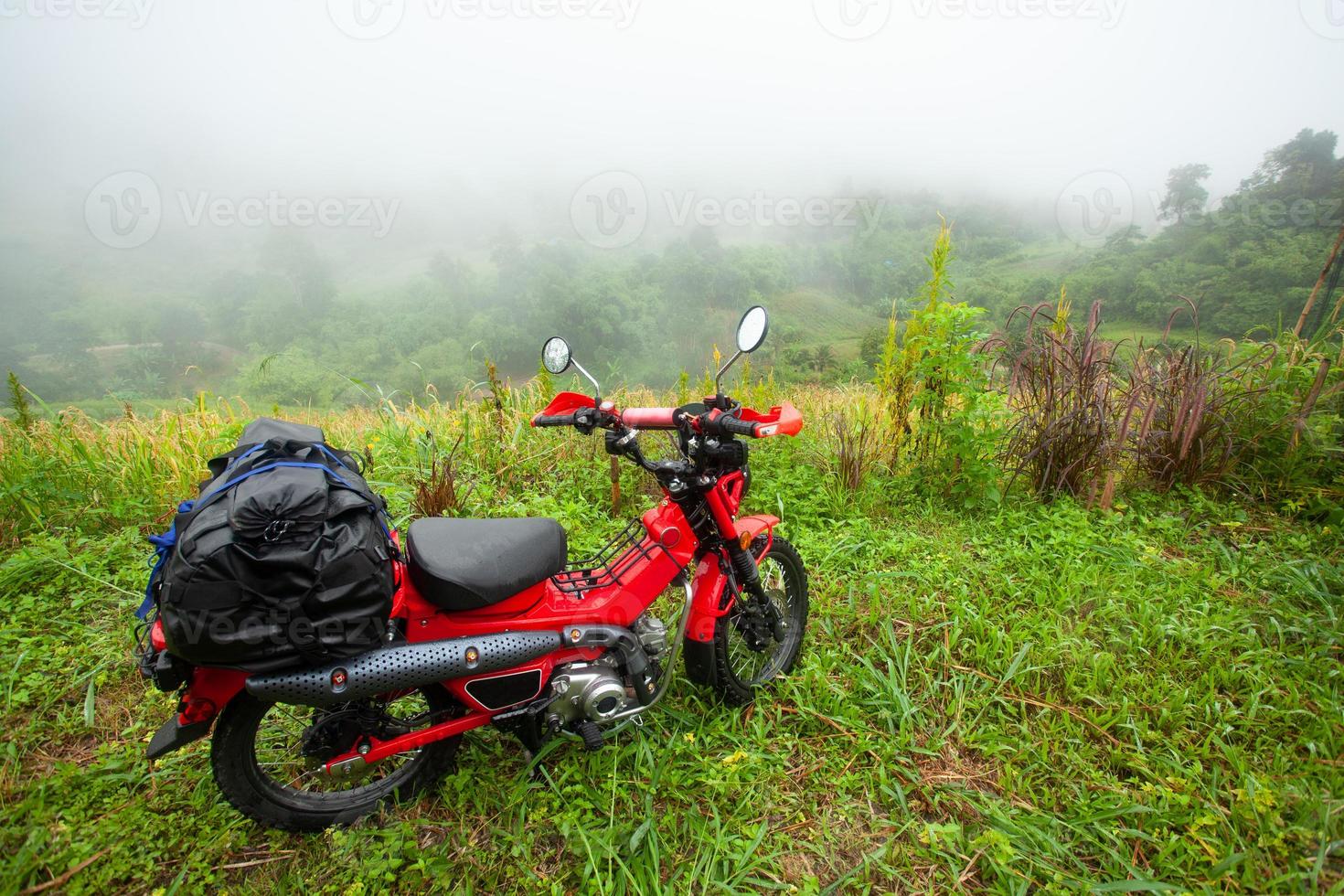 passeio de motocicleta estacionado em um gramado de montanha sob chuva e nevoeiro na Tailândia foto