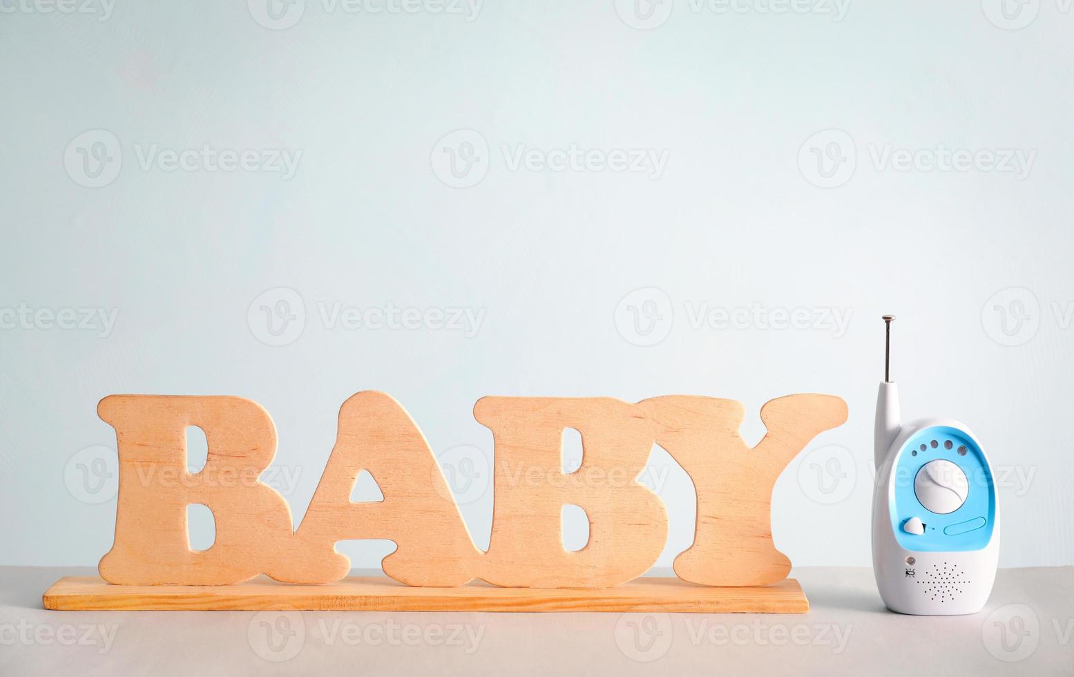 monitor de bebê e letras de madeira na mesa contra a cor de fundo foto