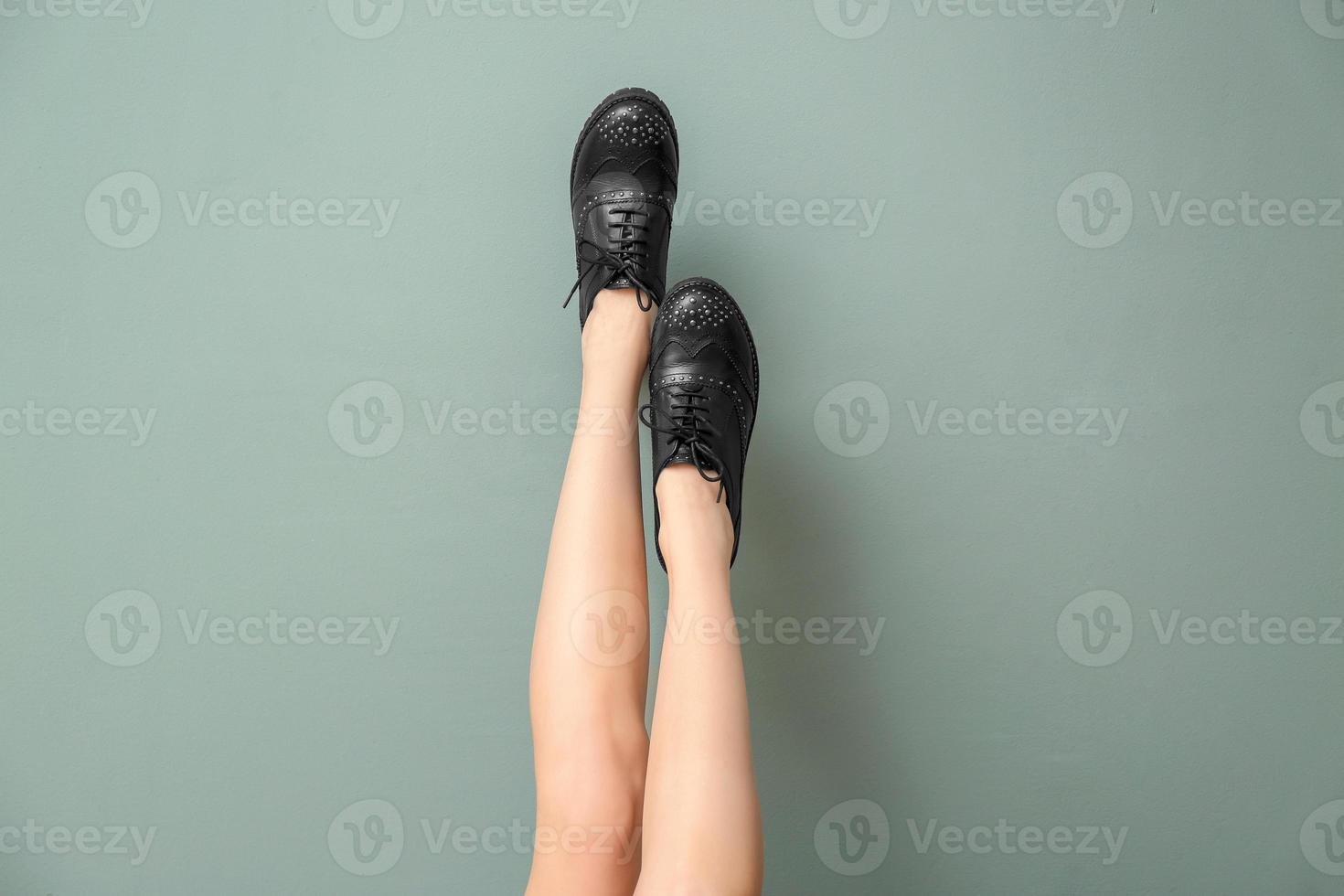 pernas de mulher jovem em elegantes sapatos casuais na cor de fundo foto