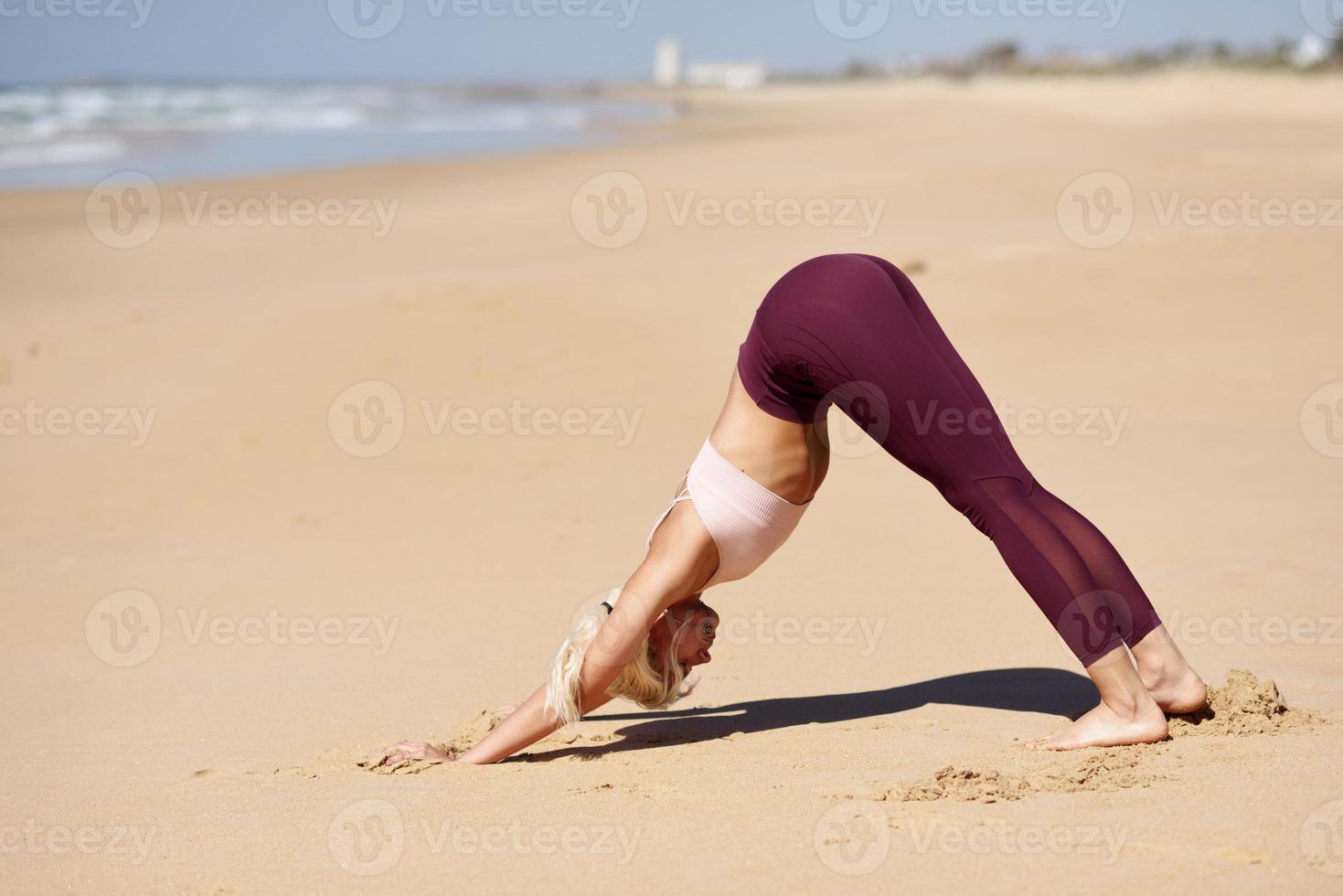 mulher loira caucasiana praticando ioga na praia foto