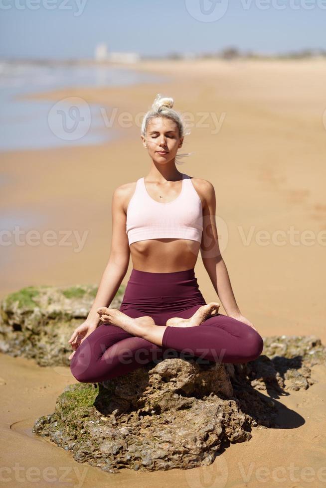 mulher loira caucasiana praticando ioga na praia foto