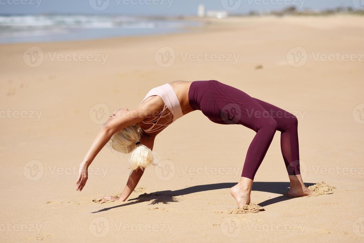 mulher loira caucasiana praticando ioga na praia foto