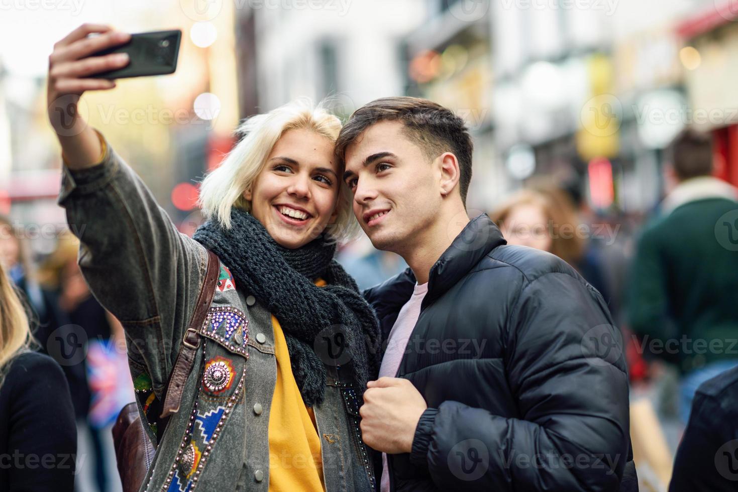 casal feliz de turistas tomando selfie em uma rua movimentada. foto