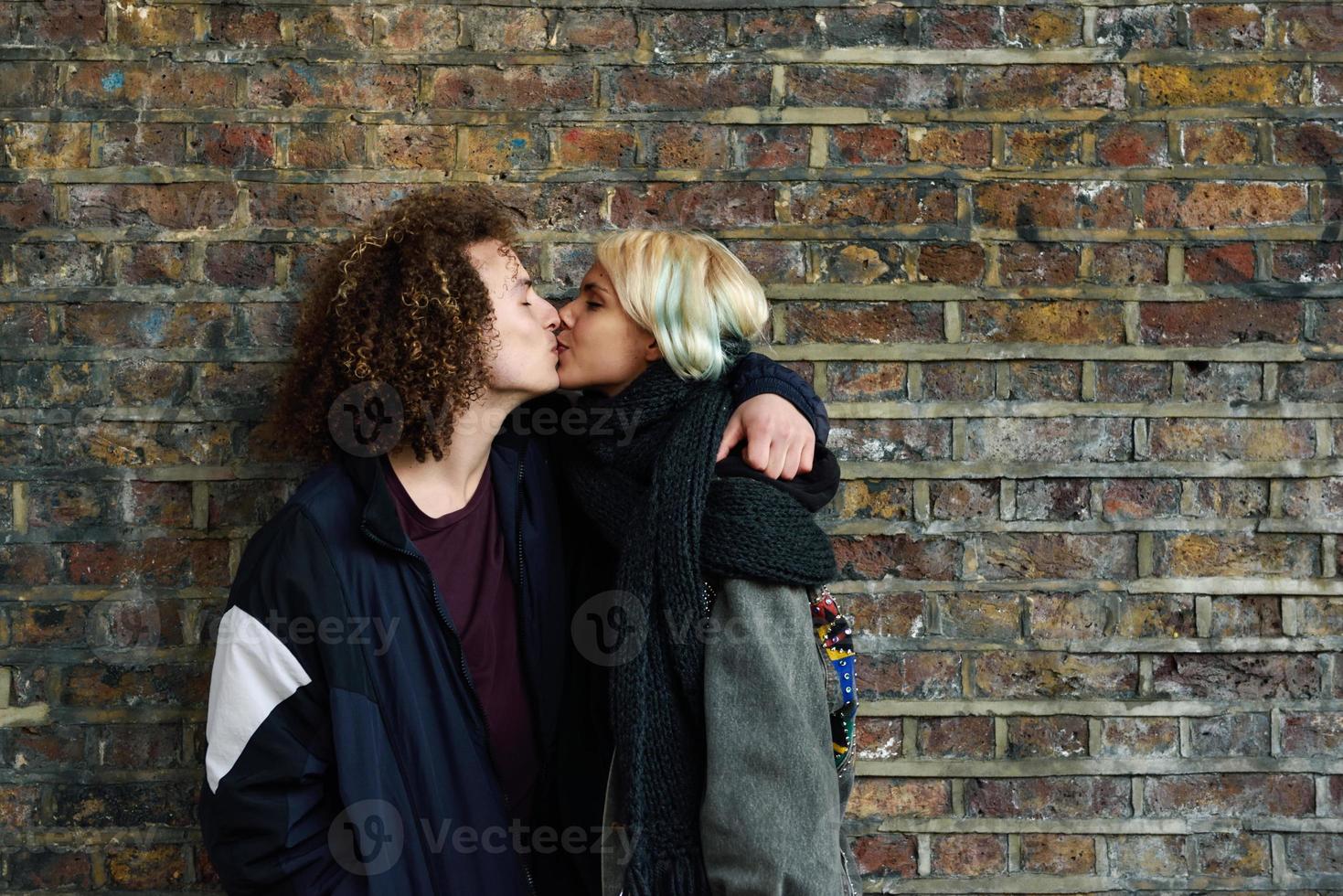 jovem casal curtindo a cidade de Camden em frente a uma parede de tijolos típica de Londres foto