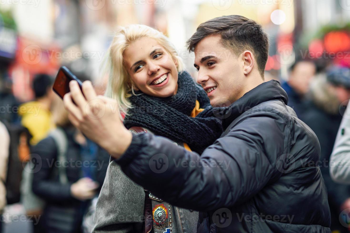 casal feliz de turistas tomando selfie em uma rua movimentada. foto