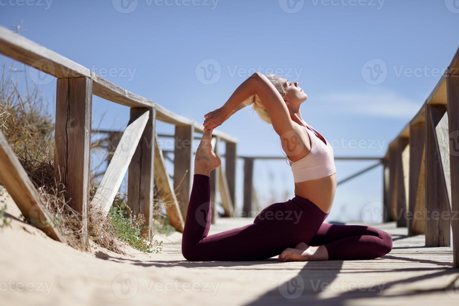 mulher loira caucasiana praticando ioga na praia foto