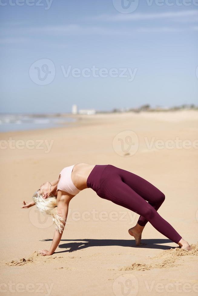 mulher loira caucasiana praticando ioga na praia foto