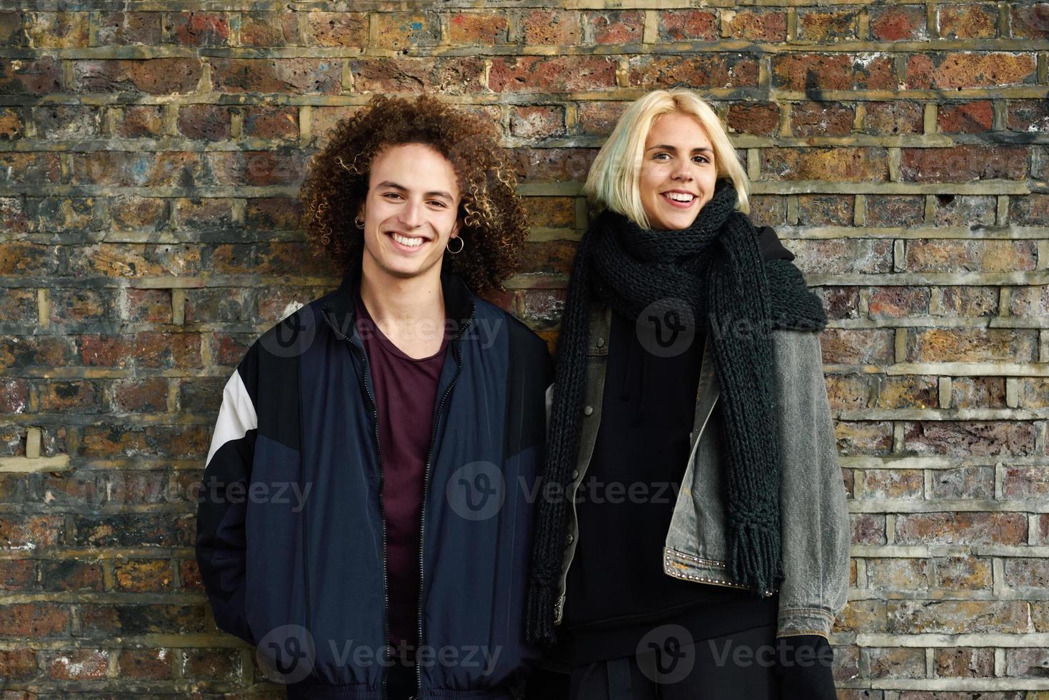 jovem casal curtindo a cidade de Camden em frente a uma parede de tijolos típica de Londres foto