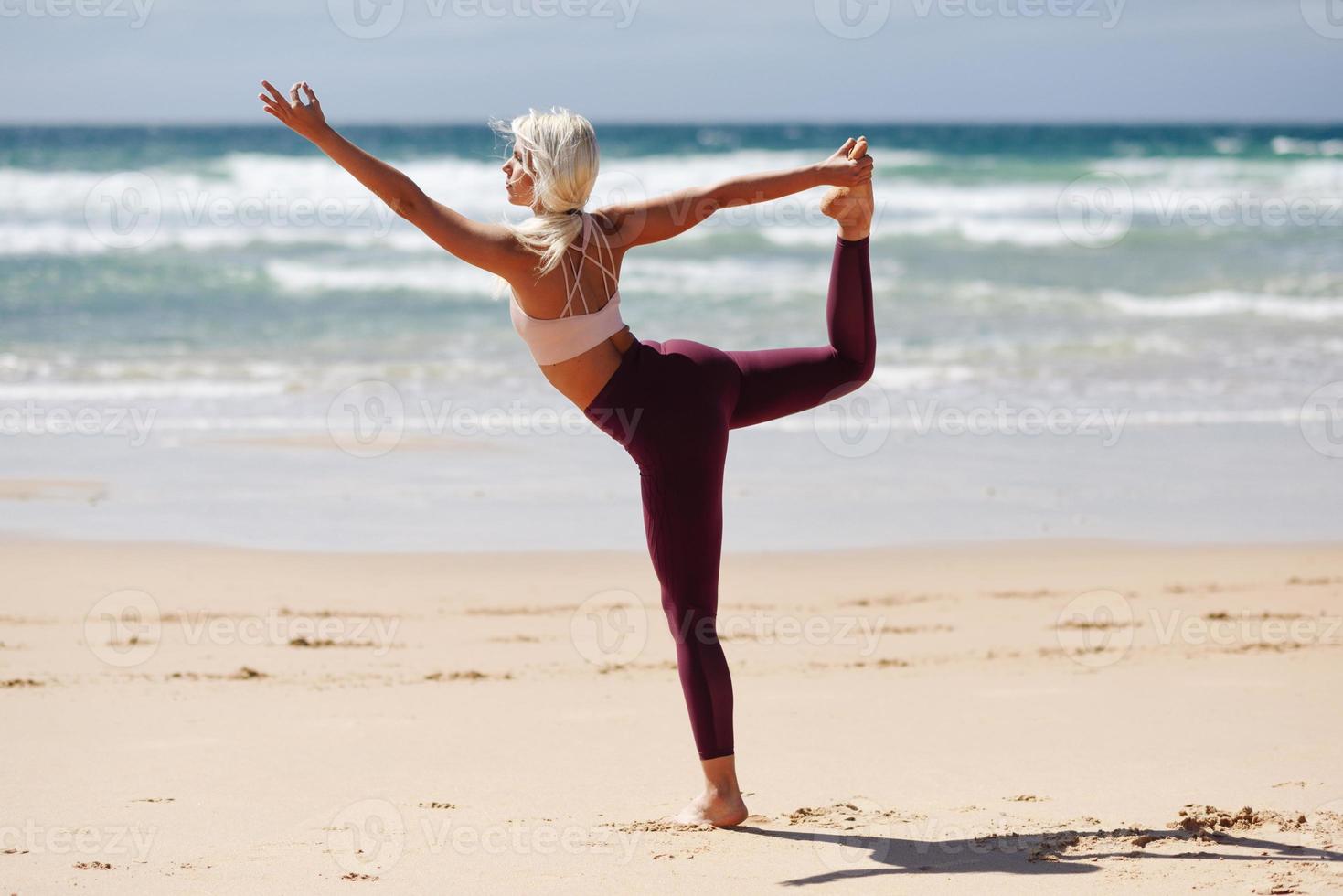 mulher loira caucasiana praticando ioga na praia foto