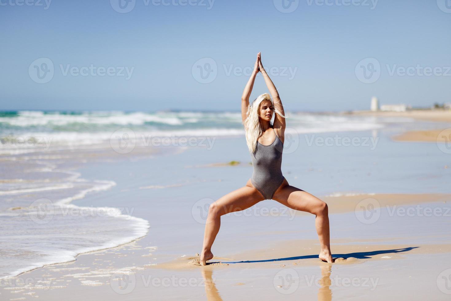 mulher loira caucasiana praticando ioga na praia foto