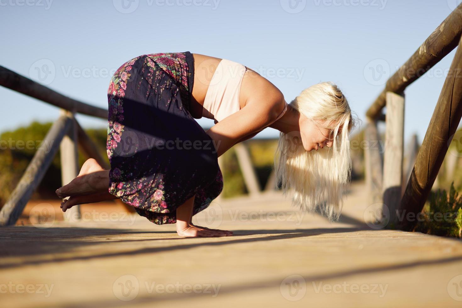 mulher caucasiana, praticando ioga na ponte de madeira. foto