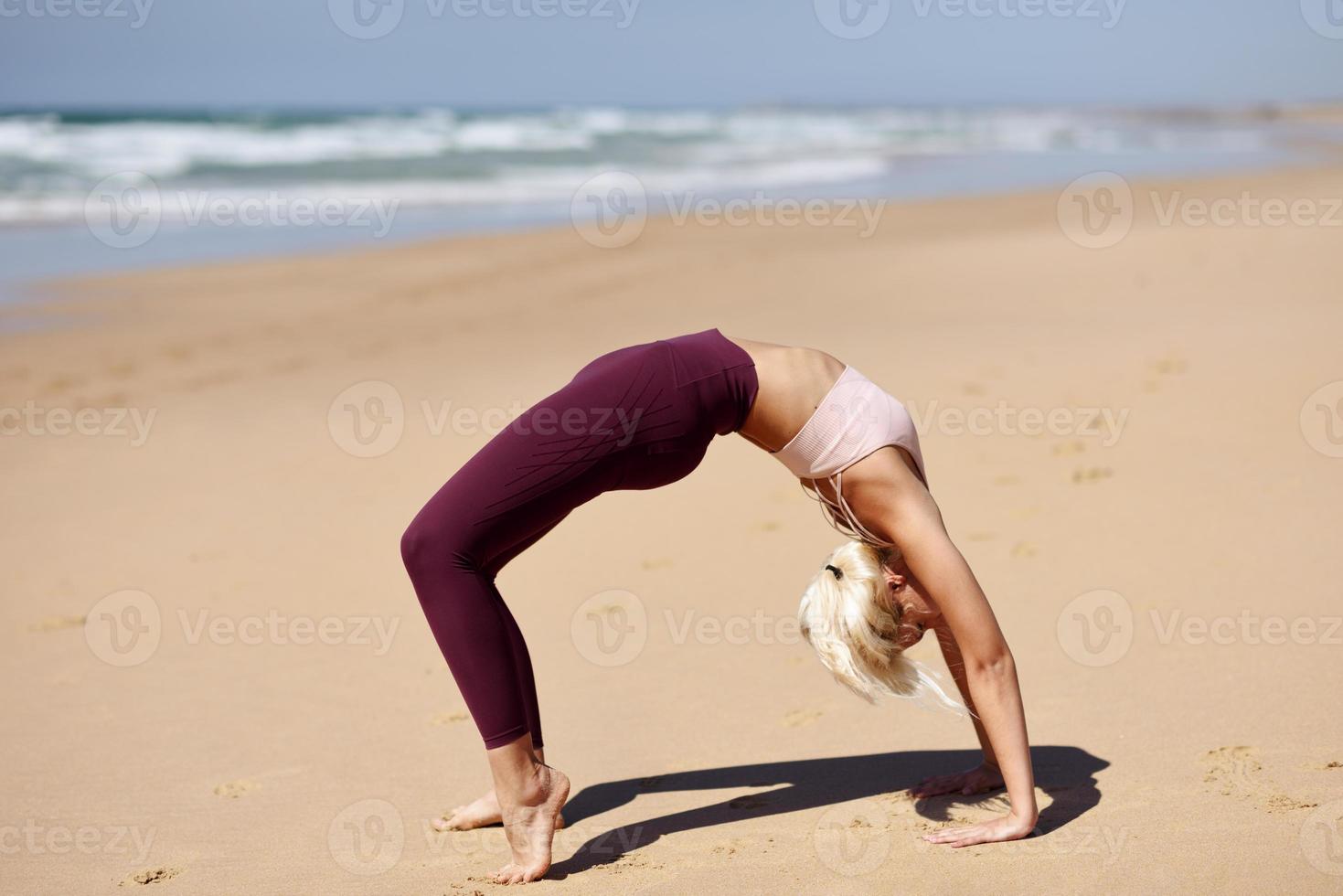 mulher loira caucasiana praticando ioga na praia foto