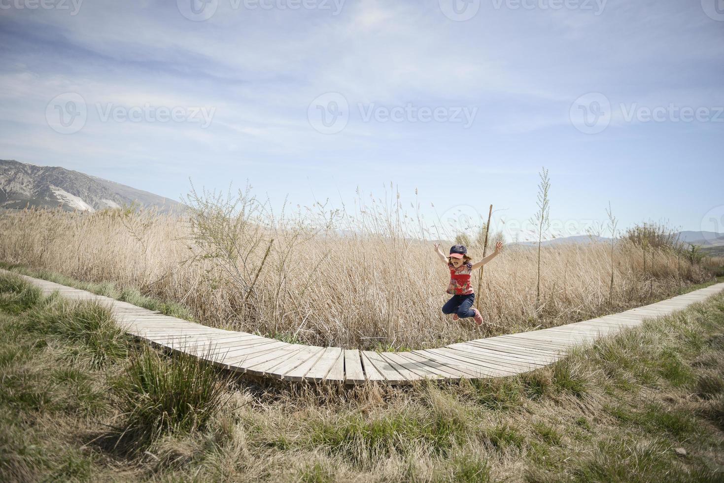 menina andando em um caminho de tábuas de madeira em um pântano foto