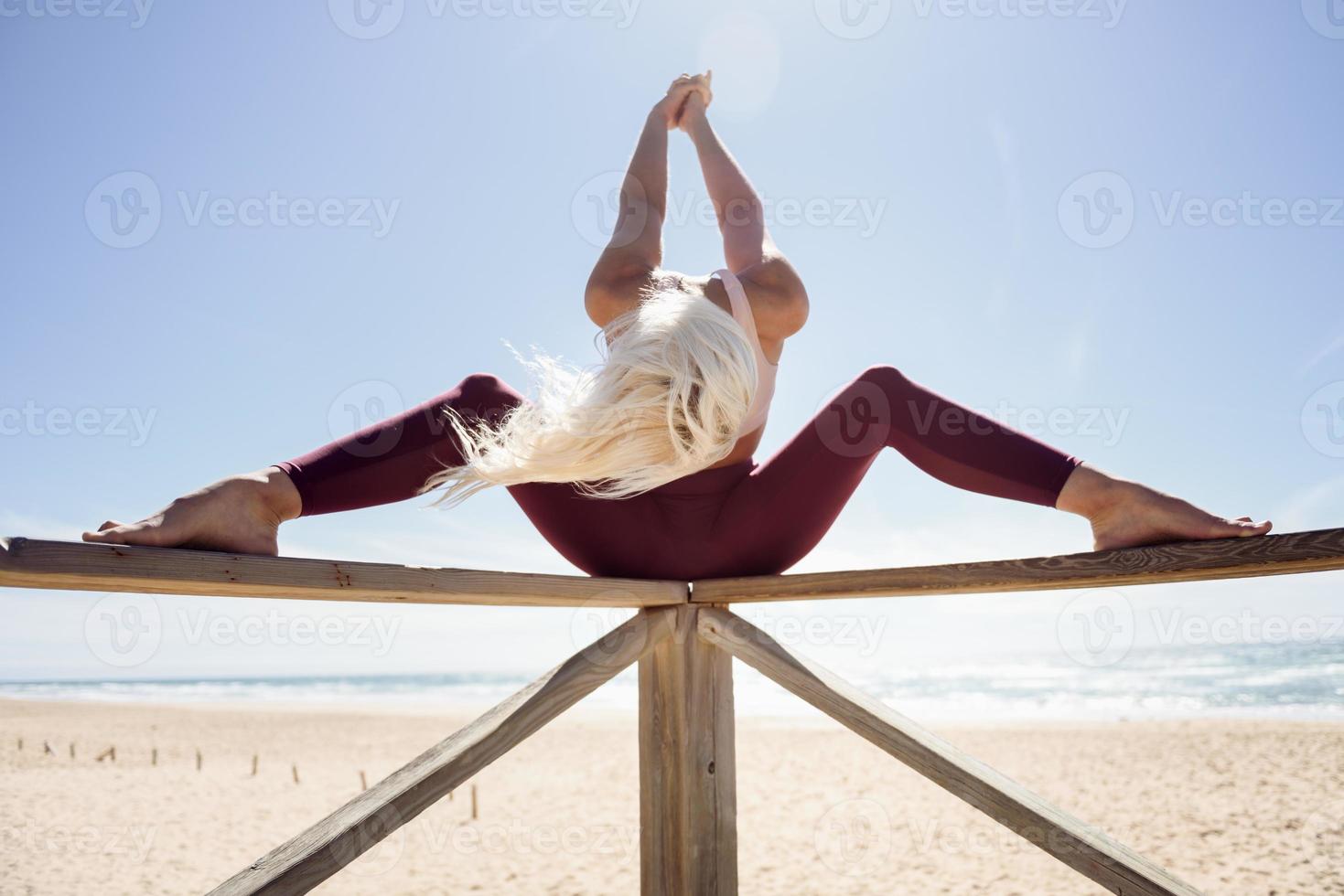 mulher loira caucasiana praticando ioga na praia foto