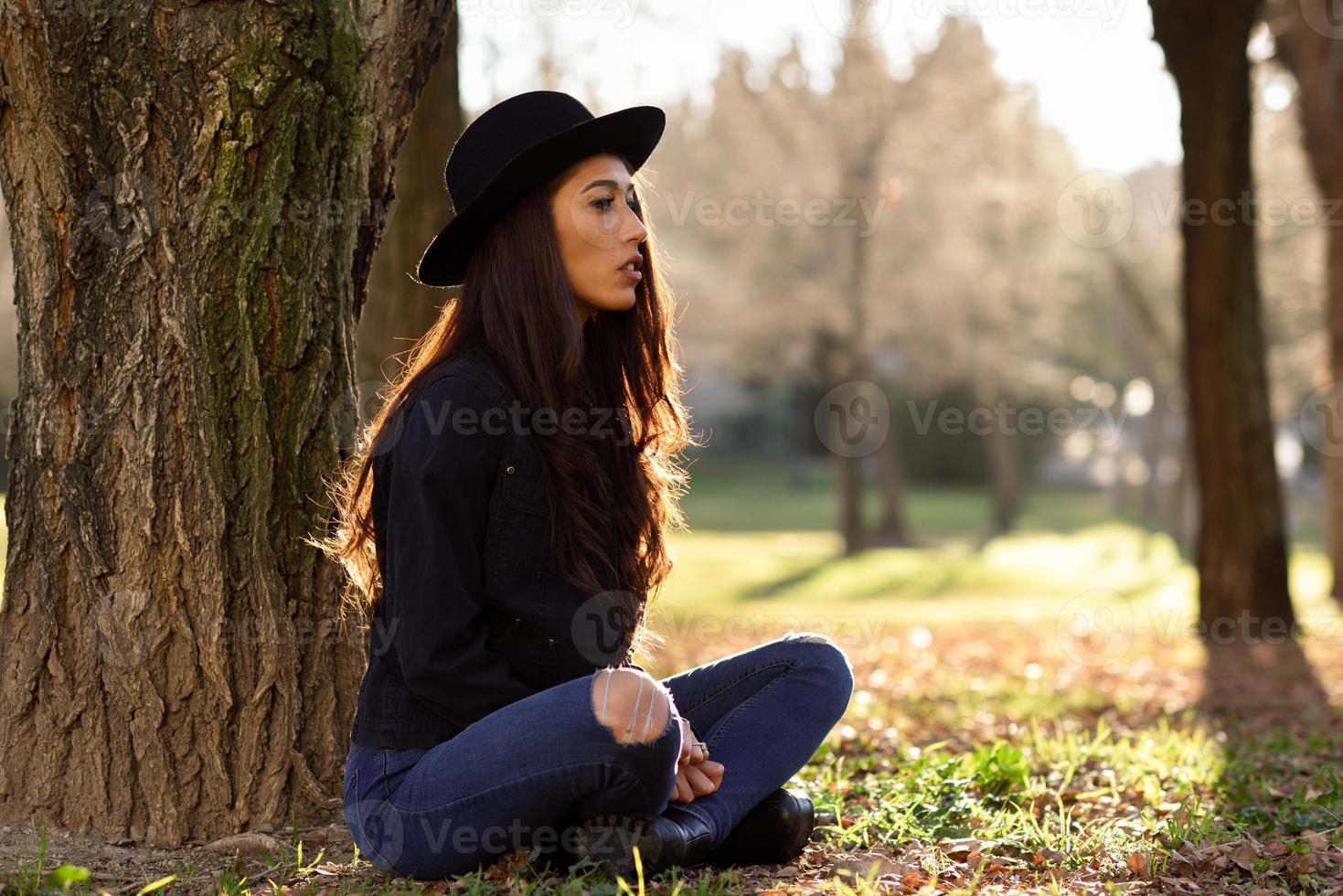 mulher pensativa sentada sozinha ao ar livre com chapéu foto