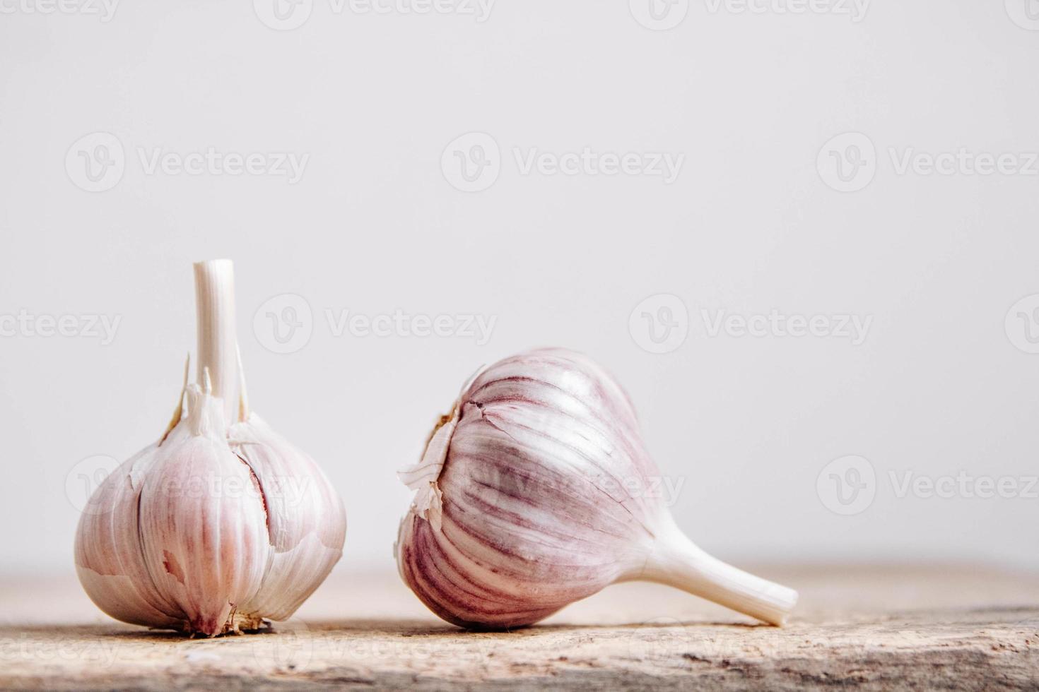 alho deitado em uma fileira em um fundo de madeira rústico foto